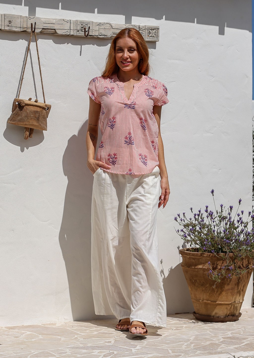 Woman wearing a 100% cotton pink striped floral short sleeve top and plain pants.