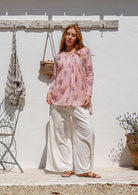 Woman wearing a pink striped cotton floral long sleeve relaxed fit V-neckline blouse paired with plain pants