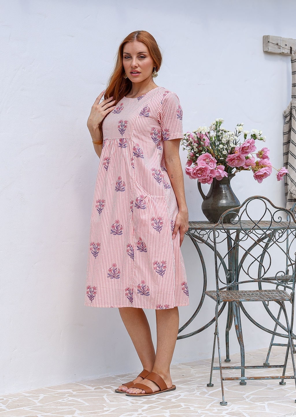 Woman poses in a pink striped white based cotton floral short sleeve dress with round neckline