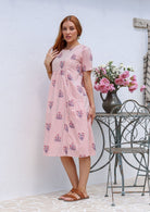 Woman poses in a pink striped white based cotton floral short sleeve dress with round neckline