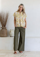 Woman wearing a navy cream based relaxed fit, shirt style floral cotton top with plain pants.