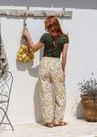 Model stands backwards wearing a 100% cotton printed wide leg cotton pants featuring pleated ankles and pockets