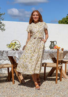 Woman wearing a cotton 1950's style short sleeved, button through cotton dress and high round neckline with one hand in pocket