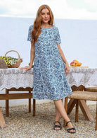 Woman poses in a white based cotton floral short sleeve dress with round neckline