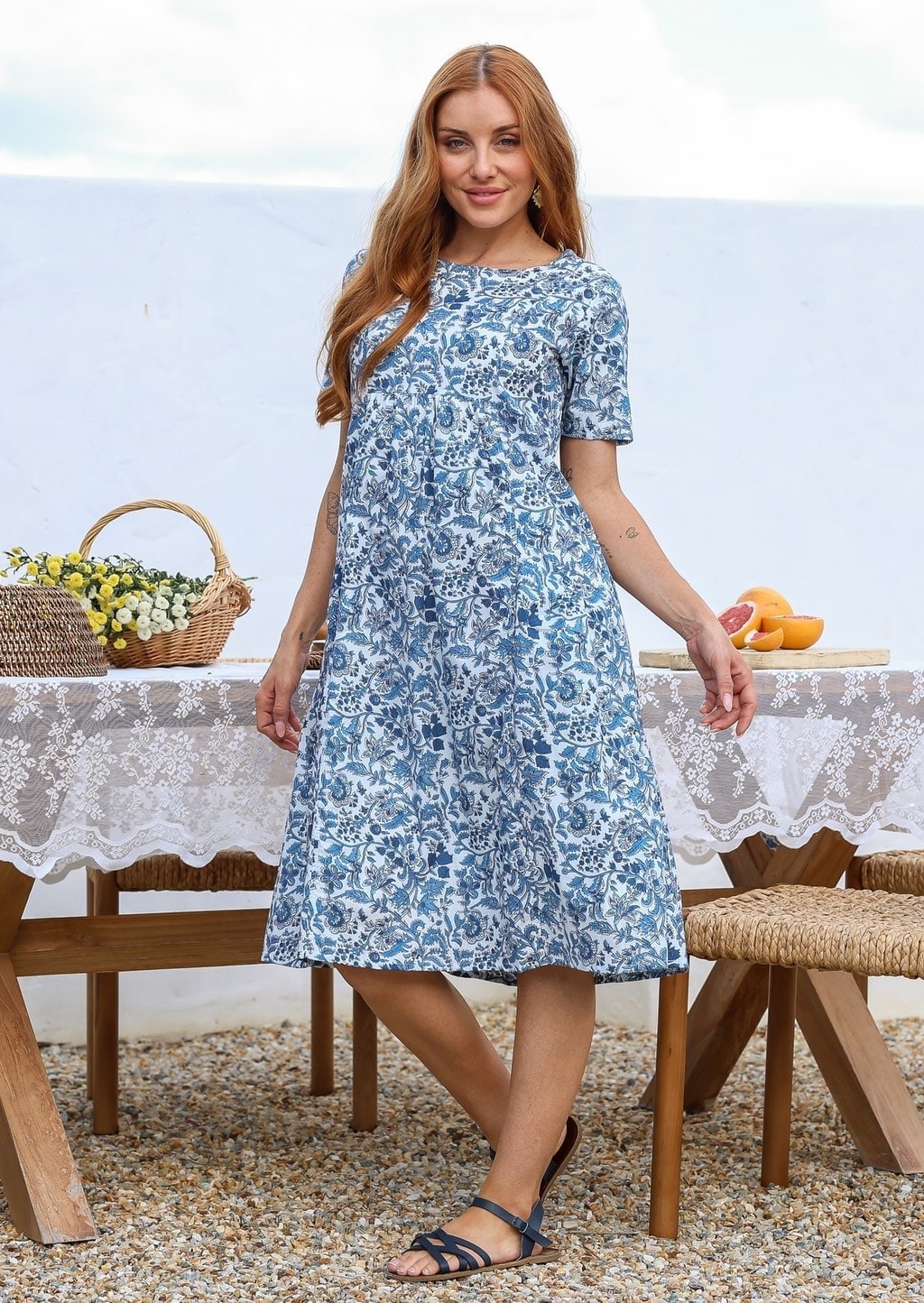 Woman wearing a 100% cotton white based blue floral print midi dress with short sleeves. 