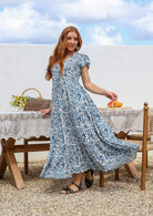 Blue and white floral print maxi dress with V-neck and short sleeves, on model, outdoor setting