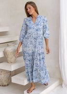 Woman wears 3 tiered maxi dress with mandarin collar and V neckline.