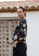 Woman wearing a black 100% cotton top with bishop sleeves and boat neckline in beautiful camellia print 