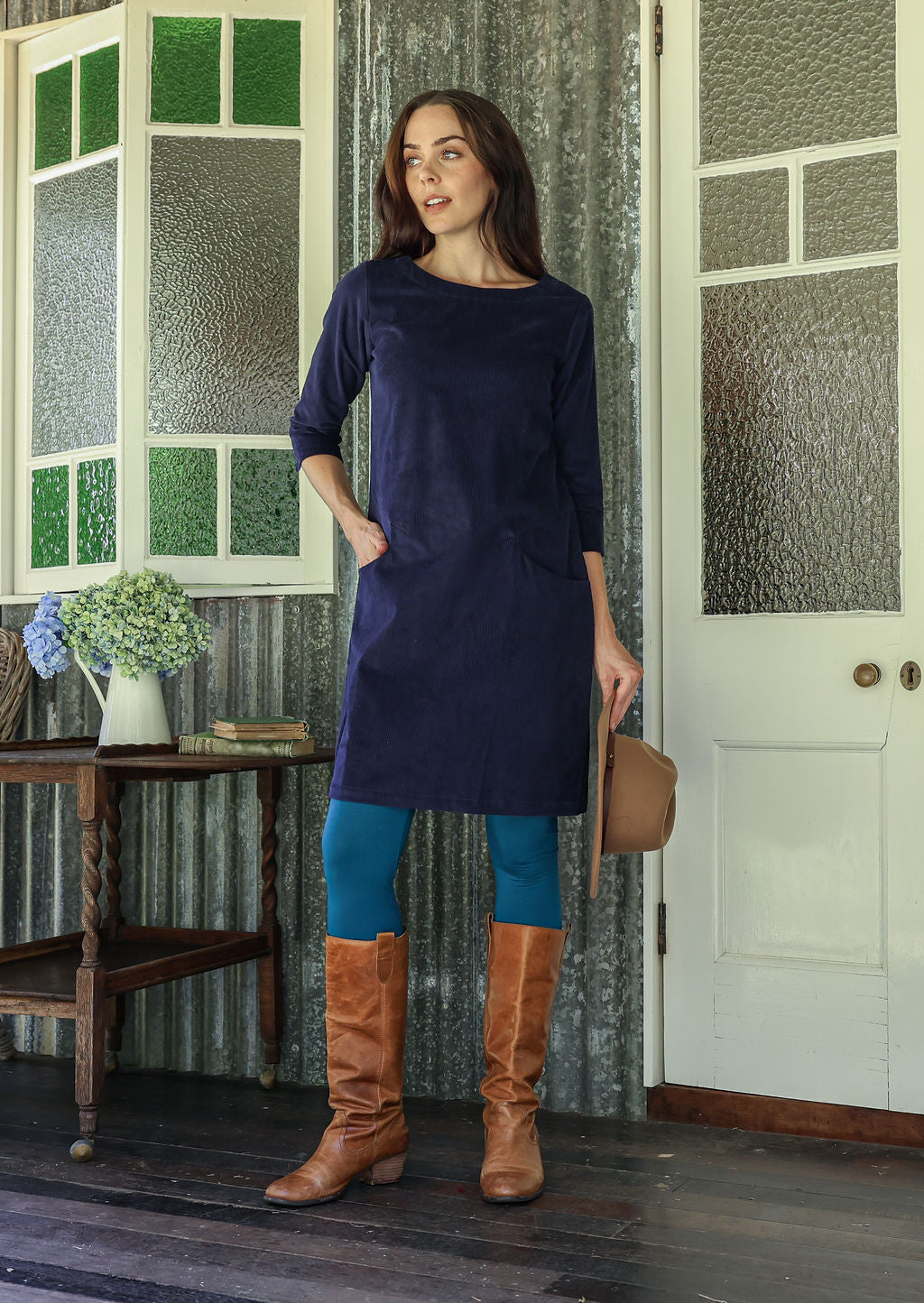 Woman wearing green corduroy A-line tunic dress with 3/4 sleeves with one hand  in pocket 