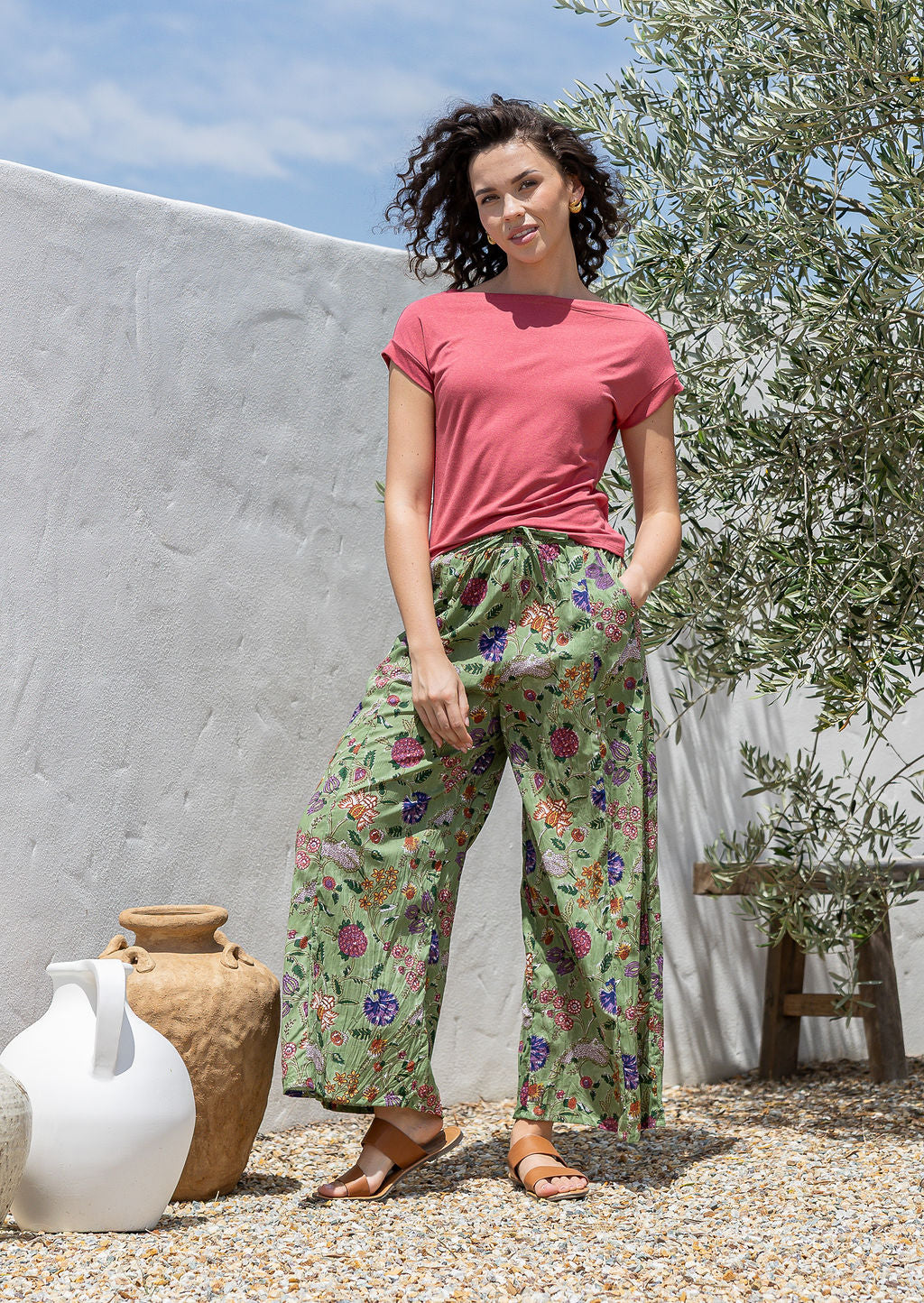 Model wears wide leg cotton floral printed pants with drawstring and hand in deep pockets.