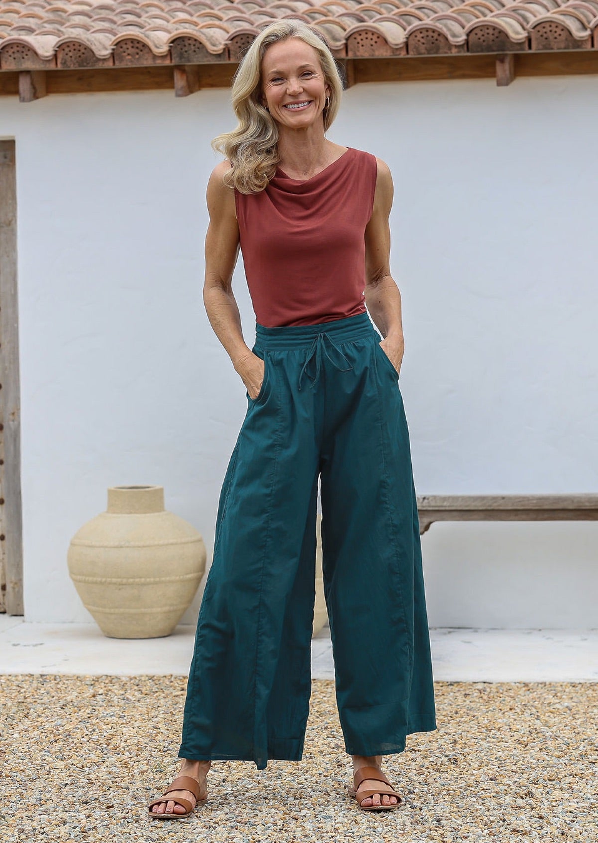 Woman wearing a terracotta sleeveless basic top and teal wide-leg cotton pants with drawstring, elasticated waist and pockets