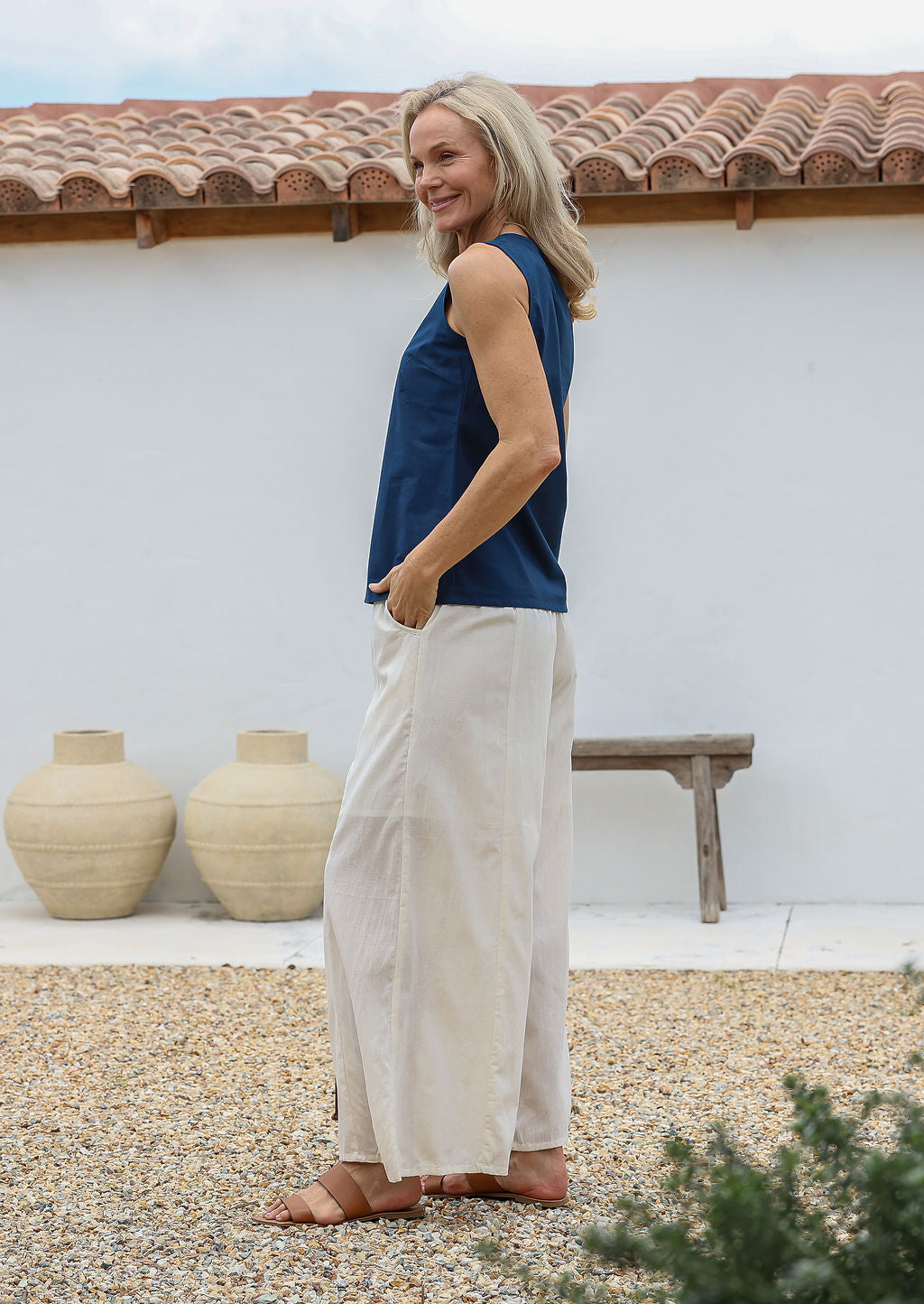 Woman wearing a blue top and white cotton pants with relaxed wide-leg fit, pockets and elastic at back of the waist.