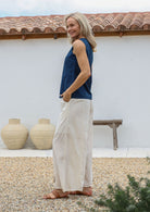 Woman wearing a blue top and white cotton pants with relaxed wide-leg fit, pockets and elastic at back of the waist.