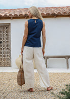 Woman standing in a back pose wearing a 100% cotton wide leg cotton pants in natural white shade with drawstring waist tie and elasticated waist.