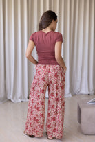Model stands backwards wearing high waisted, relaxed fit cotton pants with drawstring and a hand in pocket. 