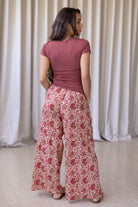 Model stands backwards wearing high waisted, relaxed fit cotton pants with drawstring and a hand in pocket. 