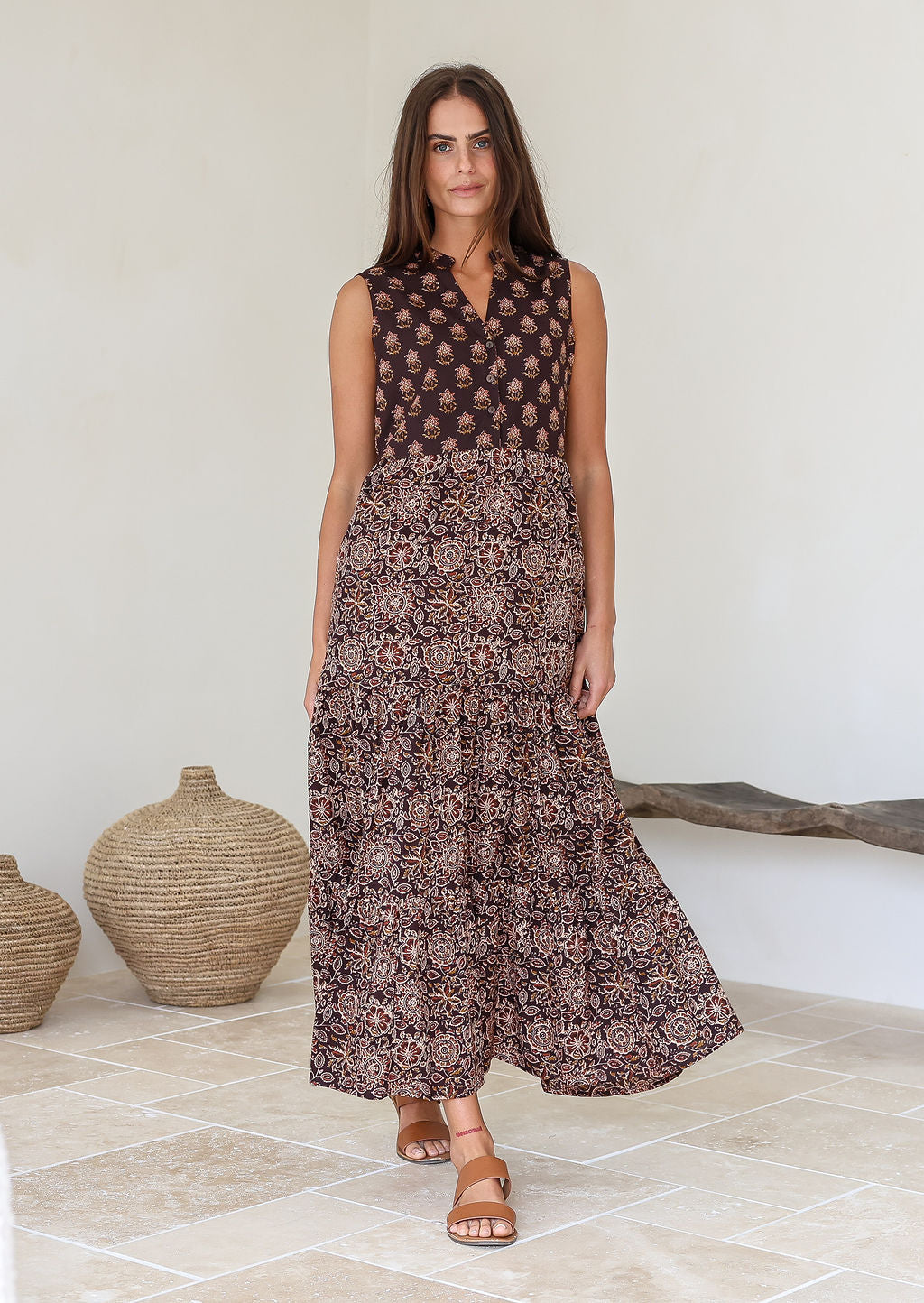 Woman wearing a brown floral dress standing in a room with decorative vases.