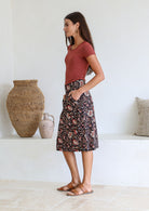 Side pose of model wearing knee length pencil skirt with top stitch detailing, pockets and hidden side zipper