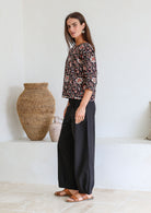 Woman stands sideways wearing relaxed fit, 100% cotton top in with loose 3/4 sleeves and wide round neckline.