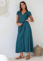 Woman wearing a teal rayon wrap dress holding the bow that is tied at the front
