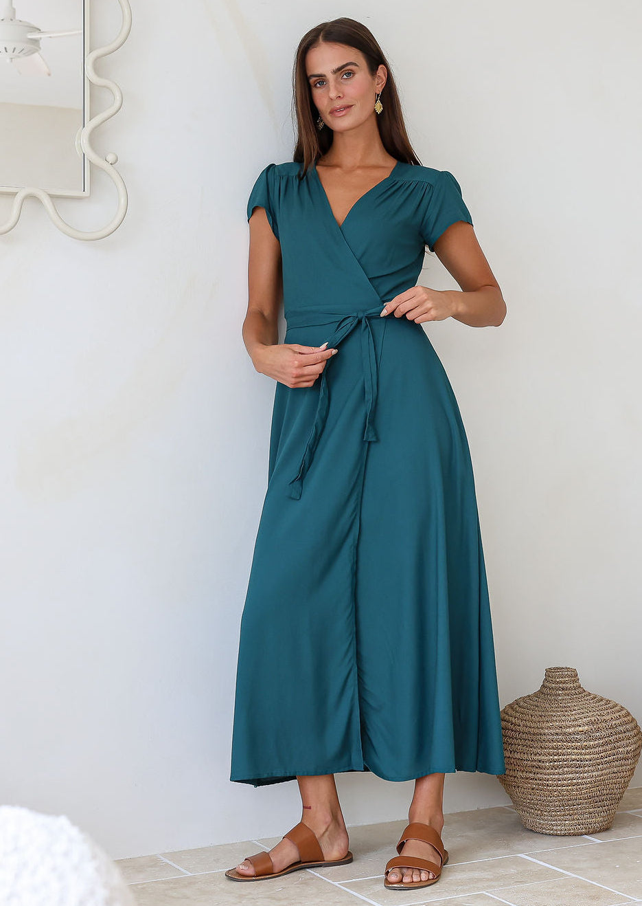 Woman wearing a teal rayon wrap dress holding the bow that is tied at the front