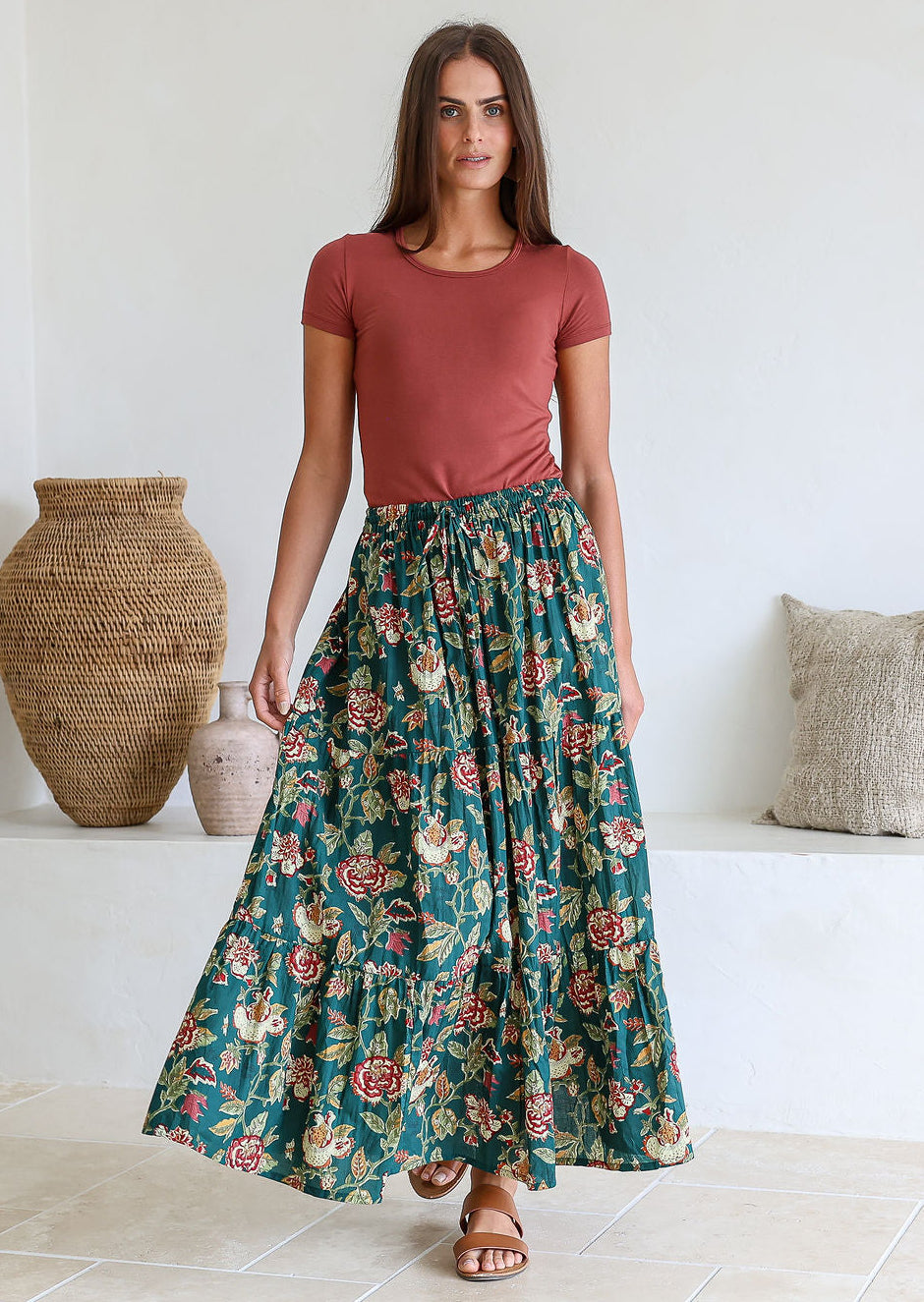 women wearing a 100% cotton maxi skirt with a plain pink top standing against a white background.