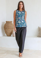 Woman standing in front of white wall wears 100% cotton sleeveless floral print top with keyhole button closure at the back