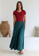 Woman wearing a maroon top and teal wide leg rayon pants with a ruched waistband