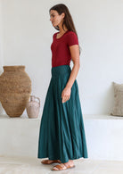 Woman wearing a maroon stretch top and teal wide leg rayon pants with sandals