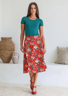 Model wearing 100% cotton knee length A-line skirt with side zipper and pockets in red based floral print