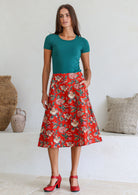 Woman is posing with one hand in pocket wearing a 100% cotton red a-line skirt.