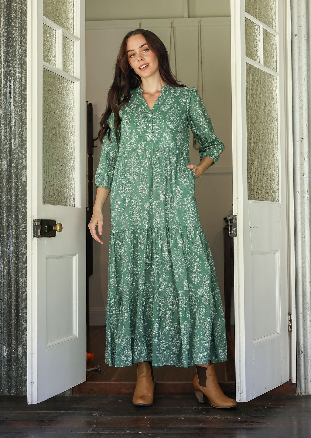 Woman poses in sage green based floral cotton maxi dress with one hand in pocket