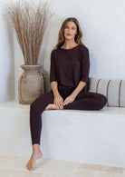 Woman sitting down wearing dark brown stretch rayon jersey top and leggings in a light room