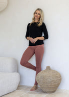Woman wearing a 100% rayon soft stretch jersey leggings in dusty pink colour standing in a minimalistic room. 
