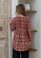 Woman standing backwards wearing a cotton floral long-sleeve shirt with a V-neckline, standing outdoor