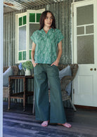 Woman wearing a floral cotton top with short folded cuff sleeves, collar and V neckline