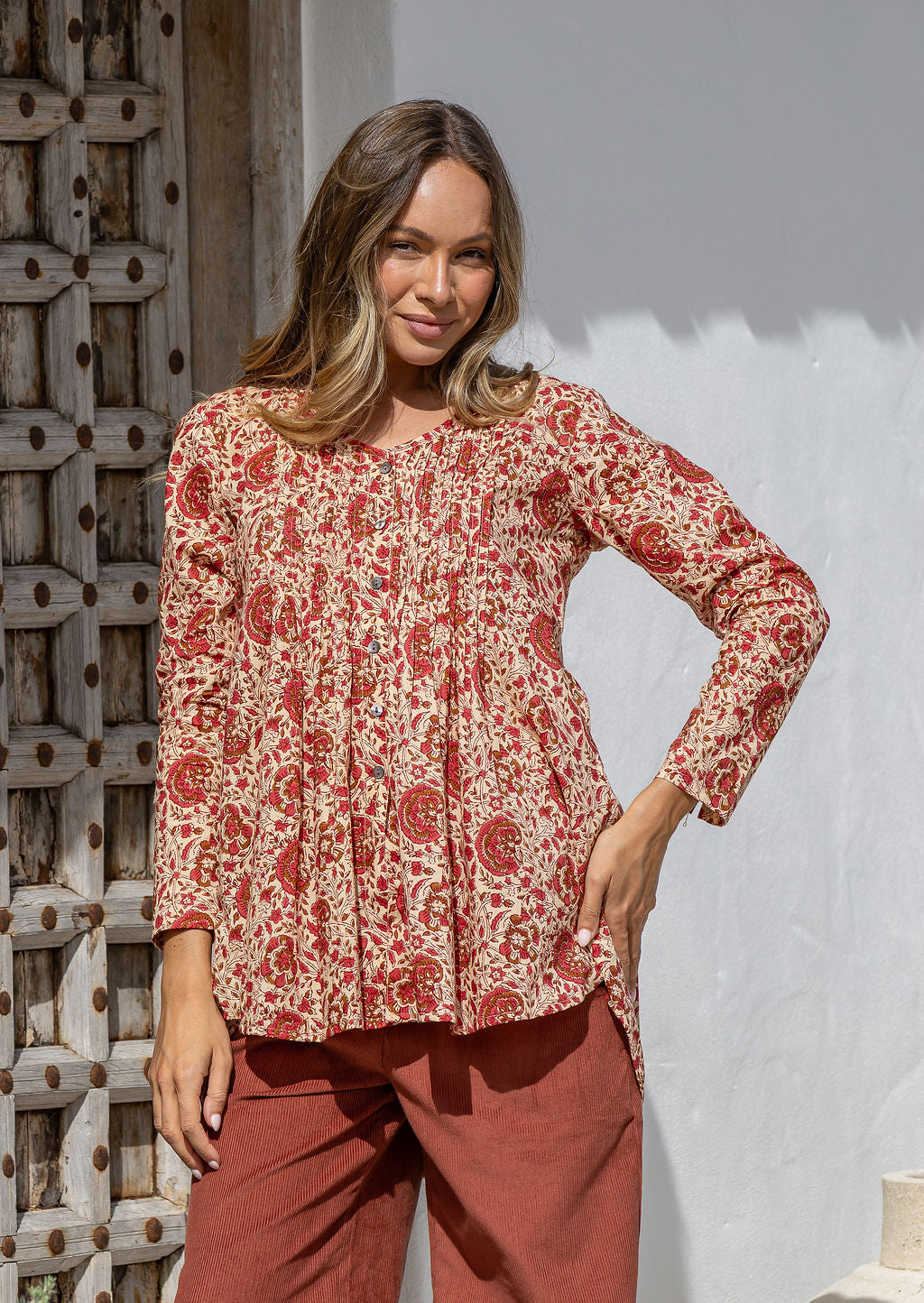 Woman wearing a cream based cotton floral long sleeve relaxed fit blouse with a V-neckline