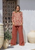 Woman wearing a cream based floral cotton long sleeve shirt with pin tucks across the back of the bodice, the back of shirt is longer than front