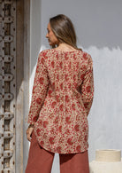 Woman standing backwards wearing a cotton floral long-sleeve shirt with a V-neckline, standing outdoor