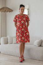 Woman wearing a 100% cotton relaxed fit dress with round neckline and short sleeves in red based multicolored floral vines print