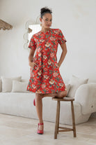 Woman poses with both hands in pockets of a 100% cotton relaxed fit dress with round neckline and short sleeves.