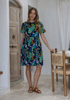 Woman wearing a 100% cotton relaxed fit dress with round neckline and short sleeves in navy based floral print.