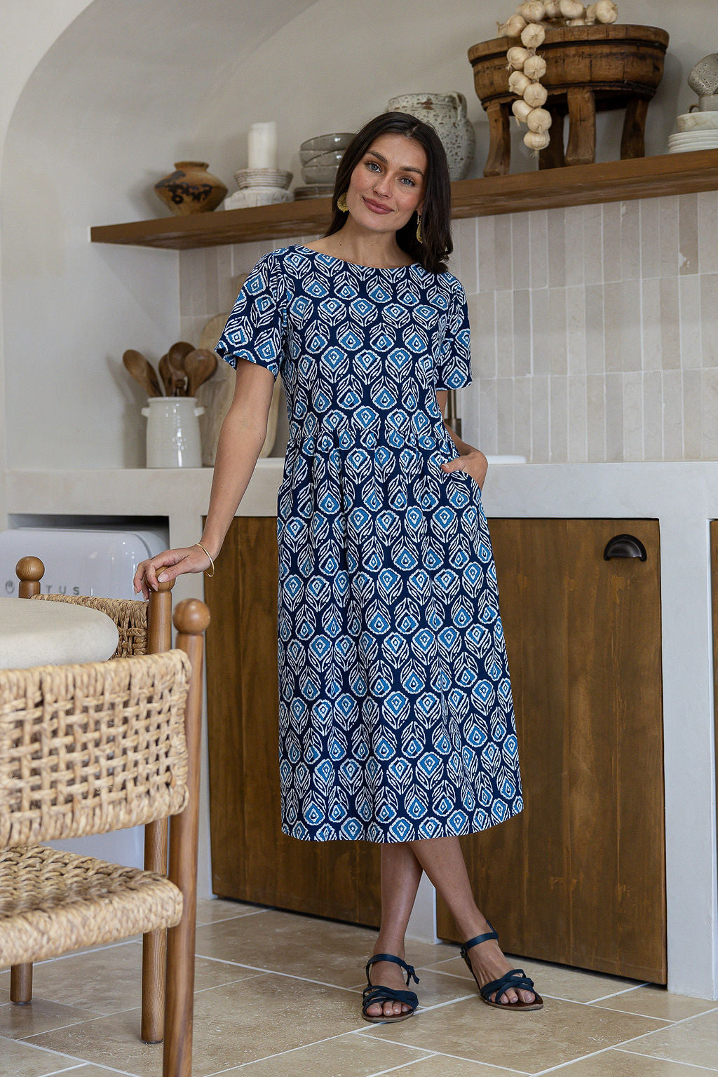 Woman wearing a 100% cotton relaxed fit dress with round neckline and one hand in pocket
