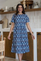 Woman wearing a 100% cotton relaxed fit dress in navy based floral print with round neckline 