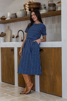 Woman wearing a 100% cotton relaxed fit dress with round neckline and one hand in pocket