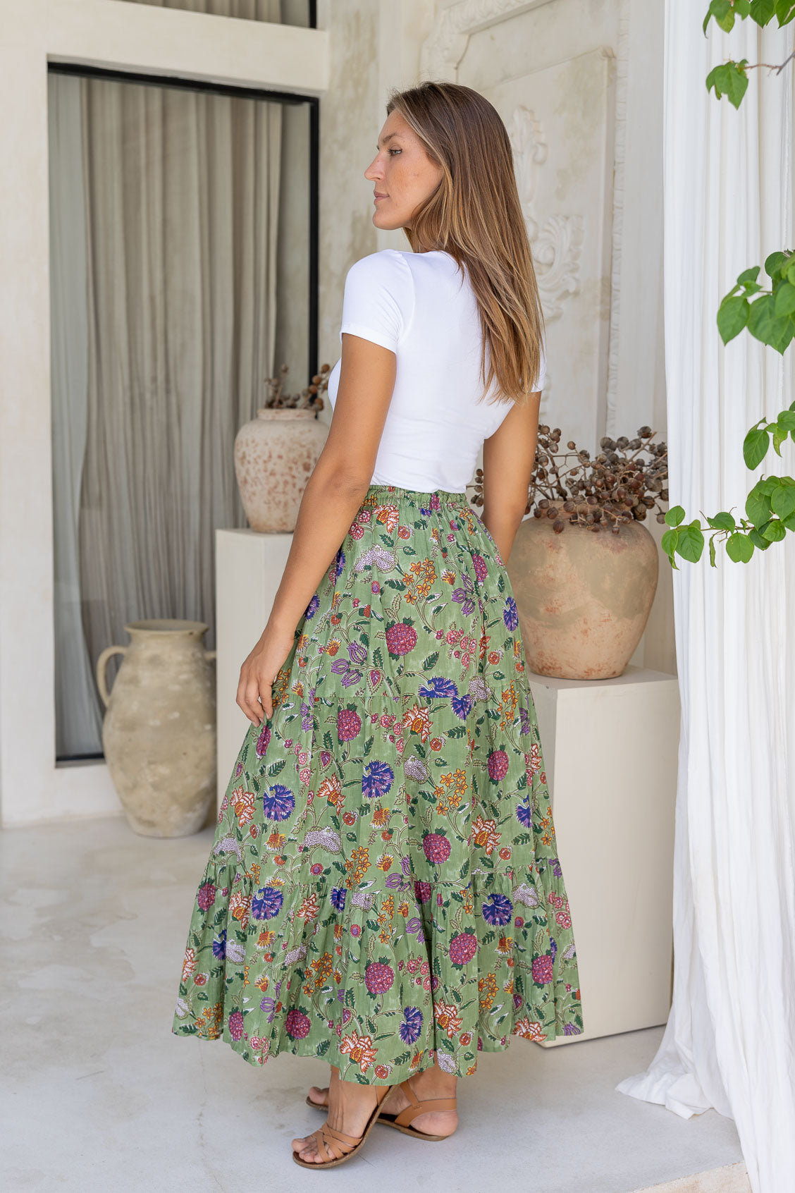 Side pose of model wearing tiered cotton maxi skirt in floral print and elasticated waist.
