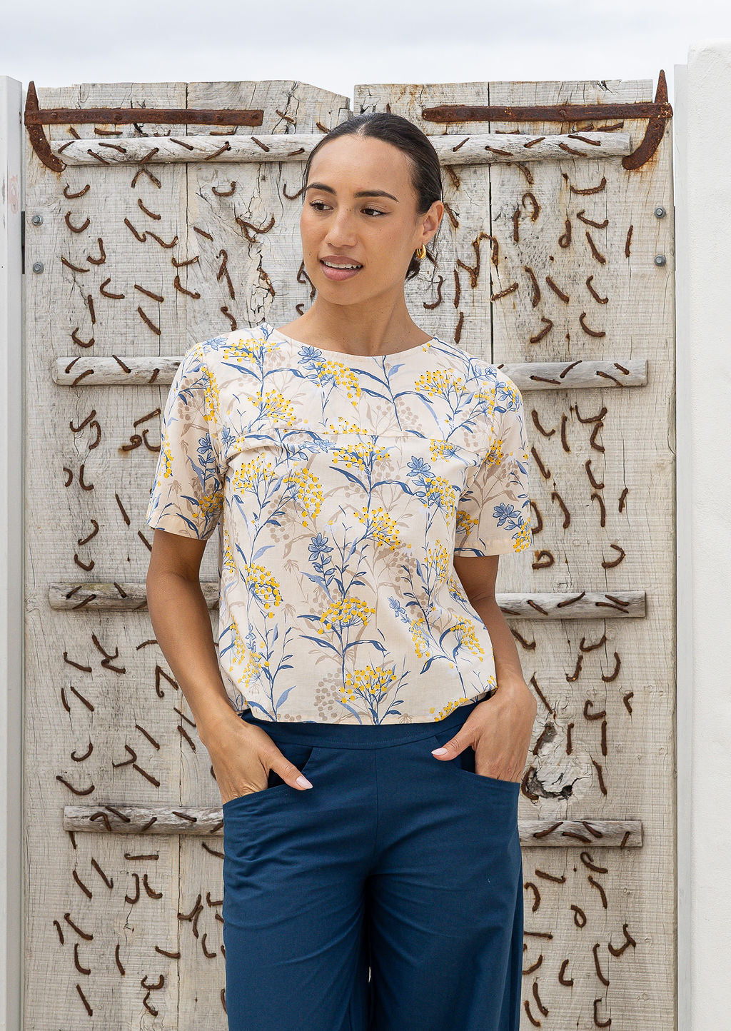 Woman wearing a 100 percent cotton, neutral based floral loose cut top with high round neckline and short sleeves