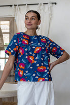 Woman wearing a royal blue based printed cotton top and white pants.