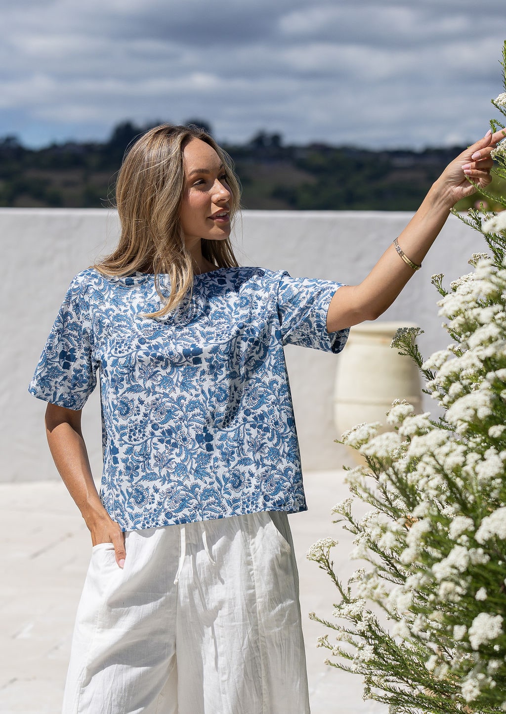 Woman wearing a cotton white based blue floral print short-sleeve top. 