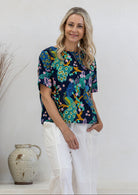 Woman wearing a navy based floral print relaxed fit cotton top with short sleeves and high neckline